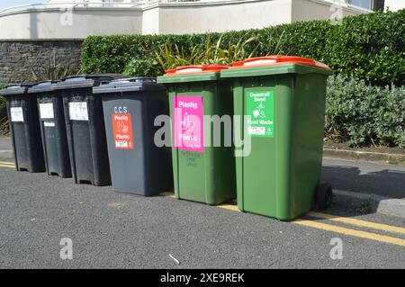 Reihe von Recycling-Wheelie-Abfalleimern bei Rotherslade bei Langland. Swansea, Wales, Vereinigtes Königreich. Mai 2024. Stockfoto