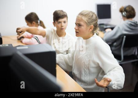Junge helfen verärgert Mädchen, um Problem auf dem Computer in der Schulklasse zu lösen Stockfoto