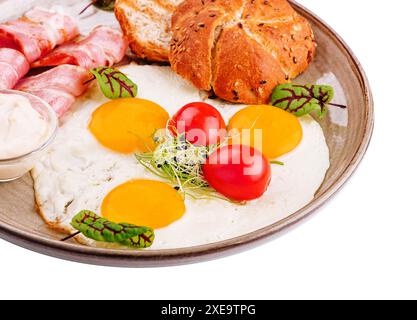 Frühstücksteller mit Spiegeleiern, Speck und Toast, isoliert auf weiß Stockfoto