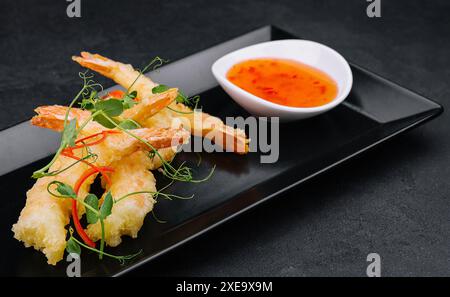 Gebratene Garnelen Tempura mit süßer Chili-Sauce auf schwarzem Steinteller Stockfoto