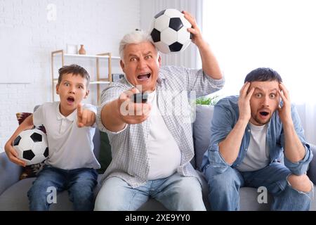 Junge mit seinem Vater und Großvater gucken Football im Wohnzimmer Stockfoto