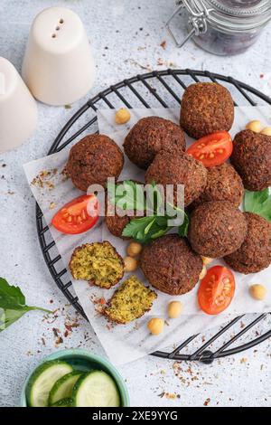 Stehen Sie mit köstlichen Falafelbällchen, Kichererbsen und Tomaten auf hellem Hintergrund Stockfoto