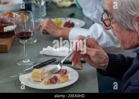 Senior-Mann, der Käse und Wurstwaren schmeckt Stockfoto