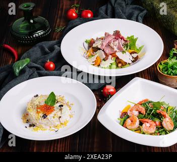 Verschiedene Salate in weißen Tellern auf einem Holztisch Stockfoto