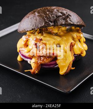 Schwarzer Burger mit Schweinefleisch auf Schwarz Stockfoto