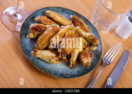 Es gibt einen herzhaften Snack auf dem Teller - große Portion gebratene Hähnchenflügel Stockfoto