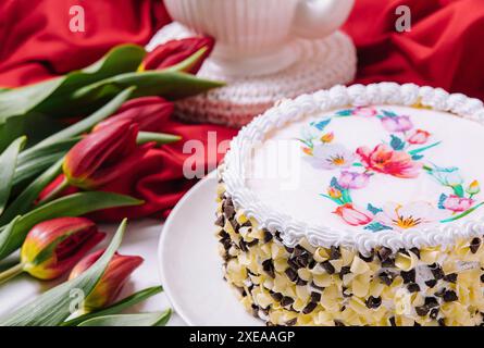 Weißer Kuchen mit Creme in der Nähe von roten Tulpen Stockfoto