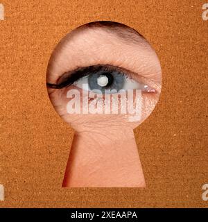 Frau, die durch das Schlüsselloch in dunkeloranger Oberfläche schaut Stockfoto
