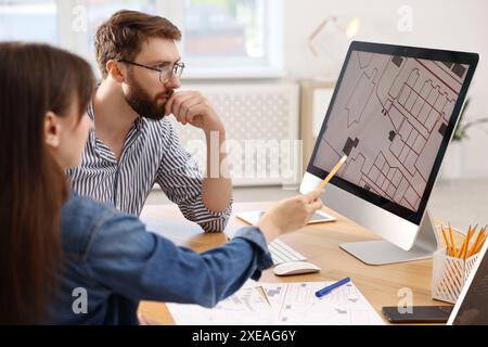 Kartografen arbeiten mit Katasterkarten am Computer am Tisch im Büro Stockfoto