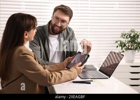 Kartografen arbeiten mit Katasterkarten auf Tablets am weißen Tisch im Büro Stockfoto