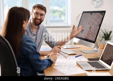 Kartografen arbeiten mit Katasterkarten am Computer am Tisch im Büro Stockfoto