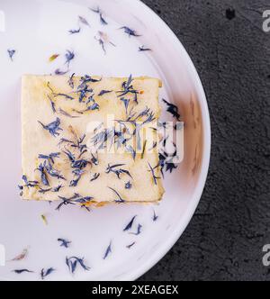 Französischer Mille-Feuille-Kuchen mit Vanillecreme, verziert mit blauen Blütenblättern Stockfoto