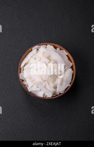 Weiße trockene Kokosflocken in einer Holzschale, die für die Zubereitung von Desserts vorbereitet ist Stockfoto