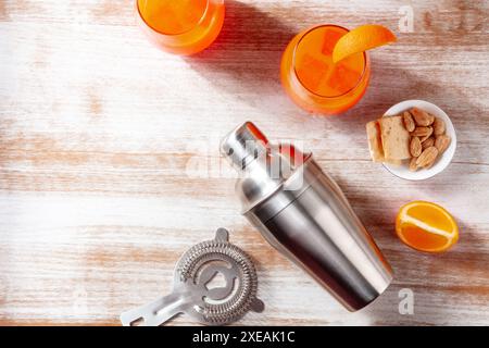 Orange Cocktails und ein Shaker, oben flach auf hölzernem Hintergrund Stockfoto