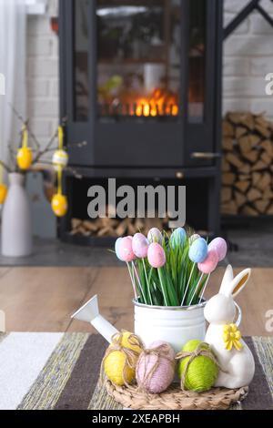 Osterdekor in der Nähe eines Kaminofens mit Kamin und Brennholz. Gemütlicher Heim-Herd im Inneren mit Topfplänen, bunten ostereiern, Stockfoto