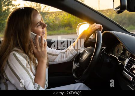 Glückliche junge Frau, die mit dem Handy spricht, während sie Auto fährt. Geschäftsfrau telefoniert im Auto. Unsicher riskante dr Stockfoto