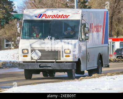 Calgary, Alberta, Kanada. März 2024. Ein Purolator-Lieferwagen, der an einem sonnigen Wintertag die Straße hinunter fährt. Stockfoto