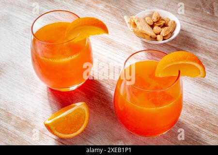Orangengetränke und ein salziger Snack auf hölzernem Hintergrund, frisch gepresster Saft Stockfoto