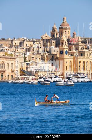 Zwei Jungen rudern im Boot auf dem Wasser des Grand Harbour mit Blick auf Birgu, Malta Stockfoto