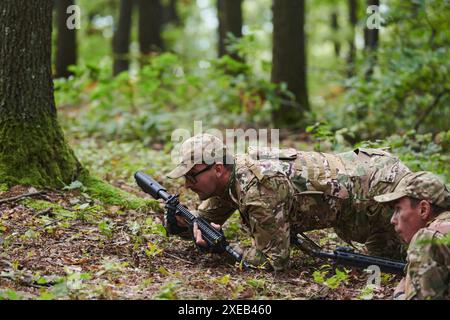 Elitesoldaten manövrieren heimlich durch den dichten Wald, getarnt in spezieller Ausrüstung, während sie sich auf eine verdeckte und str Stockfoto