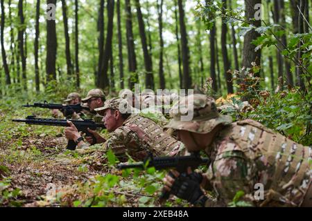 Elitesoldaten manövrieren heimlich durch den dichten Wald, getarnt in spezieller Ausrüstung, während sie sich auf eine verdeckte und str Stockfoto