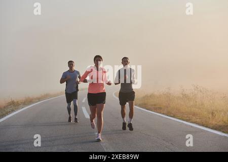 Eine Gruppe von Freunden, Athleten und Joggern nimmt die frühen Morgenstunden auf, während sie durch den nebeligen Sonnenaufgang laufen, angetrieben von der R Stockfoto