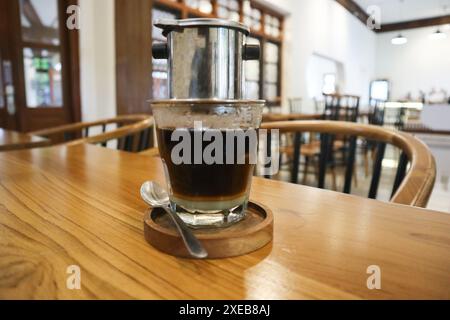 Vietnamesischer Tropf, vietnamesischer Kaffee mit Kondensmilch in Glasbechern und traditionelle Metallkaffeemaschine phin. Traditionelle Methode der Herstellung des Vietnamens Stockfoto