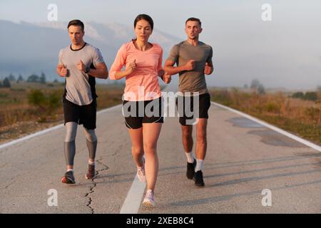 Eine Gruppe von Freunden, Athleten und Joggern nimmt die frühen Morgenstunden auf, während sie durch den nebeligen Sonnenaufgang laufen, angetrieben von der R Stockfoto