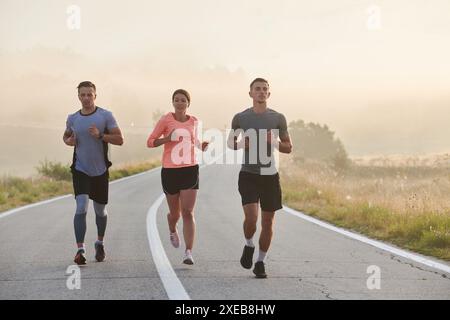 Eine Gruppe von Freunden, Athleten und Joggern nimmt die frühen Morgenstunden auf, während sie durch den nebeligen Sonnenaufgang laufen, angetrieben von der R Stockfoto