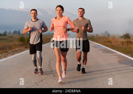 Eine Gruppe von Freunden, Athleten und Joggern nimmt die frühen Morgenstunden auf, während sie durch den nebeligen Sonnenaufgang laufen, angetrieben von der R Stockfoto