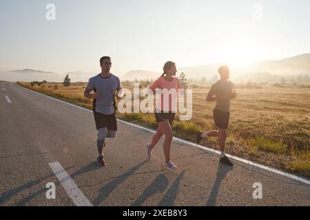 Eine Gruppe von Freunden, Athleten und Joggern nimmt die frühen Morgenstunden auf, während sie durch den nebeligen Sonnenaufgang laufen, angetrieben von der R Stockfoto