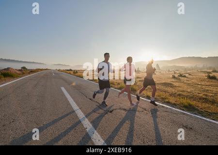 Eine Gruppe von Freunden, Athleten und Joggern nimmt die frühen Morgenstunden auf, während sie durch den nebeligen Sonnenaufgang laufen, angetrieben von der R Stockfoto