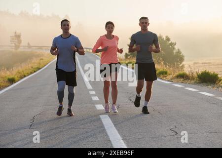 Eine Gruppe von Freunden, Athleten und Joggern nimmt die frühen Morgenstunden auf, während sie durch den nebeligen Sonnenaufgang laufen, angetrieben von der R Stockfoto