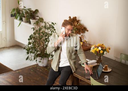 Porträt eines glücklichen jungen Managers, eines Mannes, der Verhandlungen führt, geschäftliche Gespräche am Telefon führt, auf dem Handy spricht, in dem sitzt Stockfoto