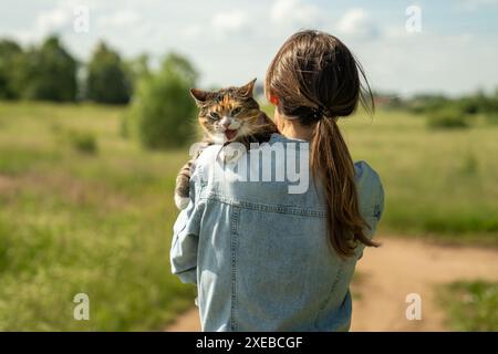 Die Katze an der Leine sitzt zum ersten Mal im Freien auf der Schulter des liebevollen Besitzers, gestresst, besorgt und ängstlich Stockfoto