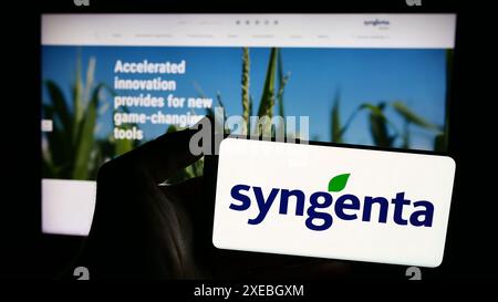 Person mit Smartphone mit Logo der Schweizer agritech-Firma Syngenta Crop Protection AG vor der Website. Schwerpunkt auf dem Display des Telefons. Stockfoto