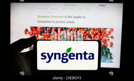 Person mit Handy mit Logo der Schweizer agritech-Gesellschaft Syngenta Crop Protection AG vor der Business-Website. Schwerpunkt auf dem Display des Telefons. Stockfoto