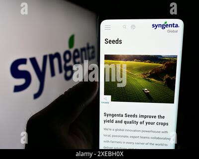 Person mit Handy mit Webseite der Schweizer agritech-Firma Syngenta Crop Protection AG vor Logo. Konzentrieren Sie sich auf die Mitte des Telefondisplays. Stockfoto