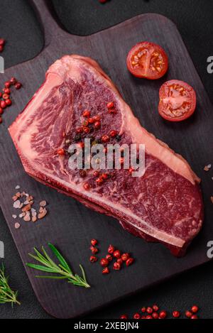 Frisches, saftiges, rohes New york Beef Steak mit Salz, Gewürzen und Kräutern Stockfoto