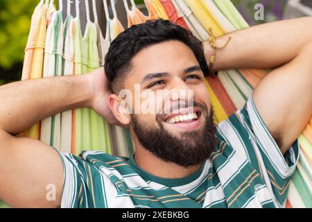 Entspannen Sie sich in der Hängematte, lächelnder Mann und genießen Sie die Freizeit im Freien Stockfoto