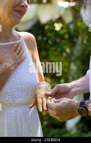Seniorenpaar tauscht bei einer Zeremonie im Freien Ringe aus, um Liebe und Engagement zu feiern Stockfoto