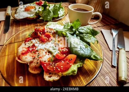 Frühstück in einem Café. Toast mit Ei, Tomaten und Spinat, dazu eine Tasse Kaffee Stockfoto