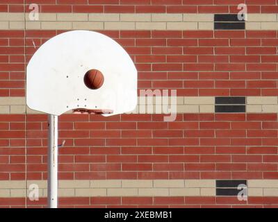 Ein Basketball, der sich rechtzeitig vor seiner Flugbahn zum festen Rand des Punktkörpers hin aufhält. Stockfoto