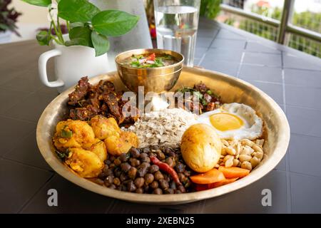 Newari Khaja Set typisch nepalesischer Thali mit Reisflocken, Choyila, Eiern, Kichererbsen, Tama, Bambussuppe, Mittagessen Aalu Sadheko Stockfoto