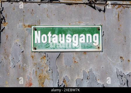 Wandbeschriftung mit abblätternder Farbe einer alten Hüttenanlage in Deutschland - Notausgang. Grüne Platte mit weißer Inschrift in deutscher Sprache. Stockfoto