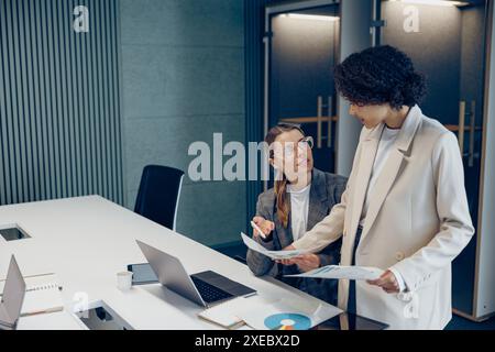 Zwei weibliche Experten für professionelle Führungskräfte diskutieren über die Zusammenarbeit mit Finanzbuchhaltungsunterlagen Stockfoto