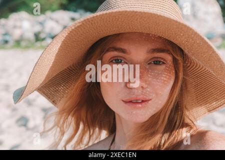 Porträt einer jungen attraktiven rothaarigen Frau mit Sommersprossen mit Strohhut Stockfoto