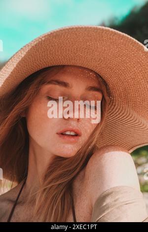 Porträt einer jungen attraktiven rothaarigen Frau mit Sommersprossen mit Strohhut Stockfoto