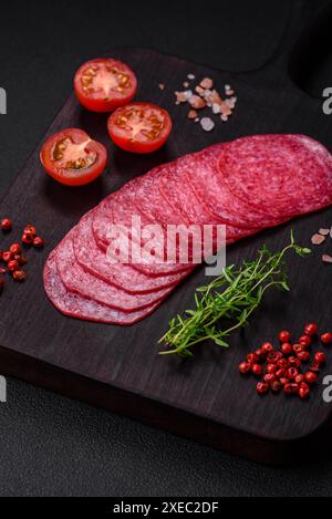 Köstliche geräucherte Salami-Wurst mit Salz, Gewürzen und in Scheiben geschnittenen Kräutern Stockfoto