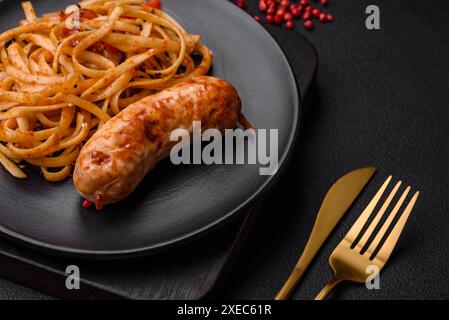 Köstliche saftige gegrillte Wurst mit Pasta oder Nudeln mit Salz, Gewürzen und Kräutern Stockfoto